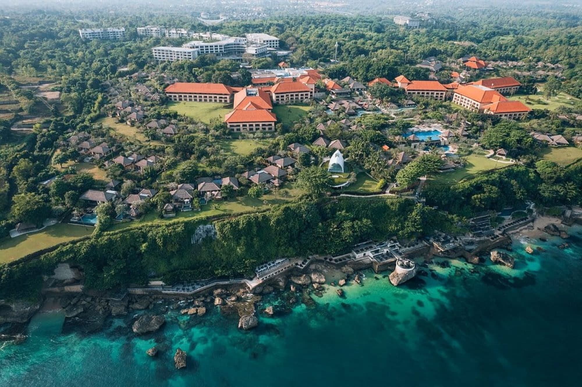 Aerial view of clifftop villas above a turquoise coastline in Bali