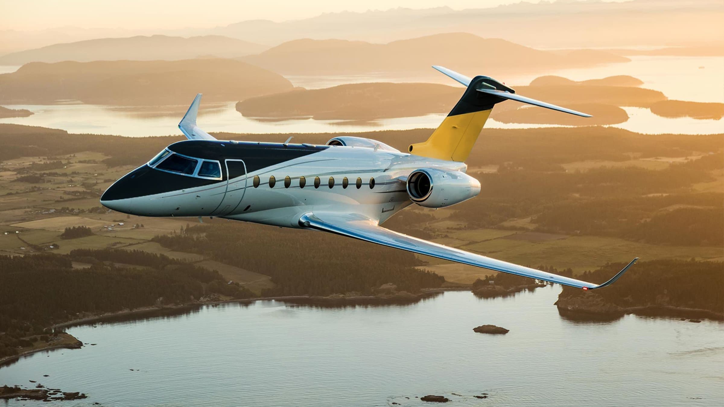 Gulfstream G280 in flight over a river valley at golden hour
